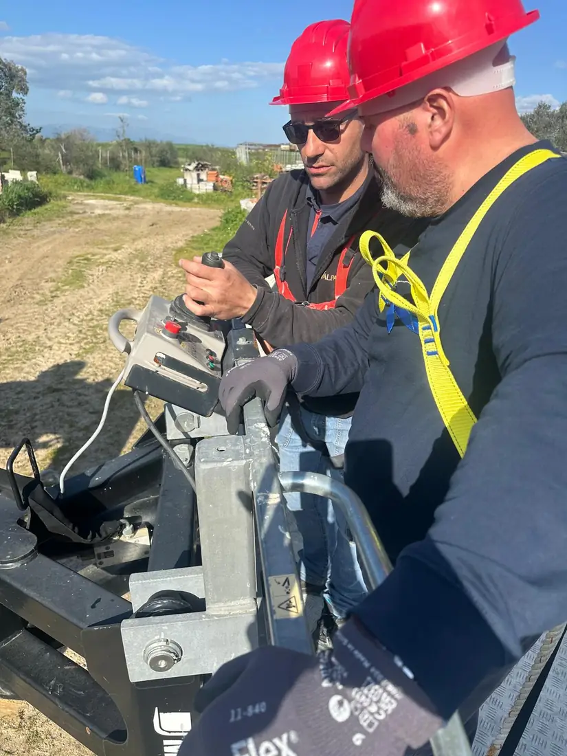 Due partecipanti manovrano il radiocomando della piattaforma con i guanti da lavoro